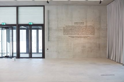 Foyer mit Eingangstüren, Wandtext zu James Simon auf Sichtbeton und Vorhang – James-Simon-Galerie, Berlin