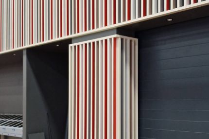 Lamellenfries und Stützenverkleidung mit roten Feldern neben Sektionaltor – Mensa Würzburg