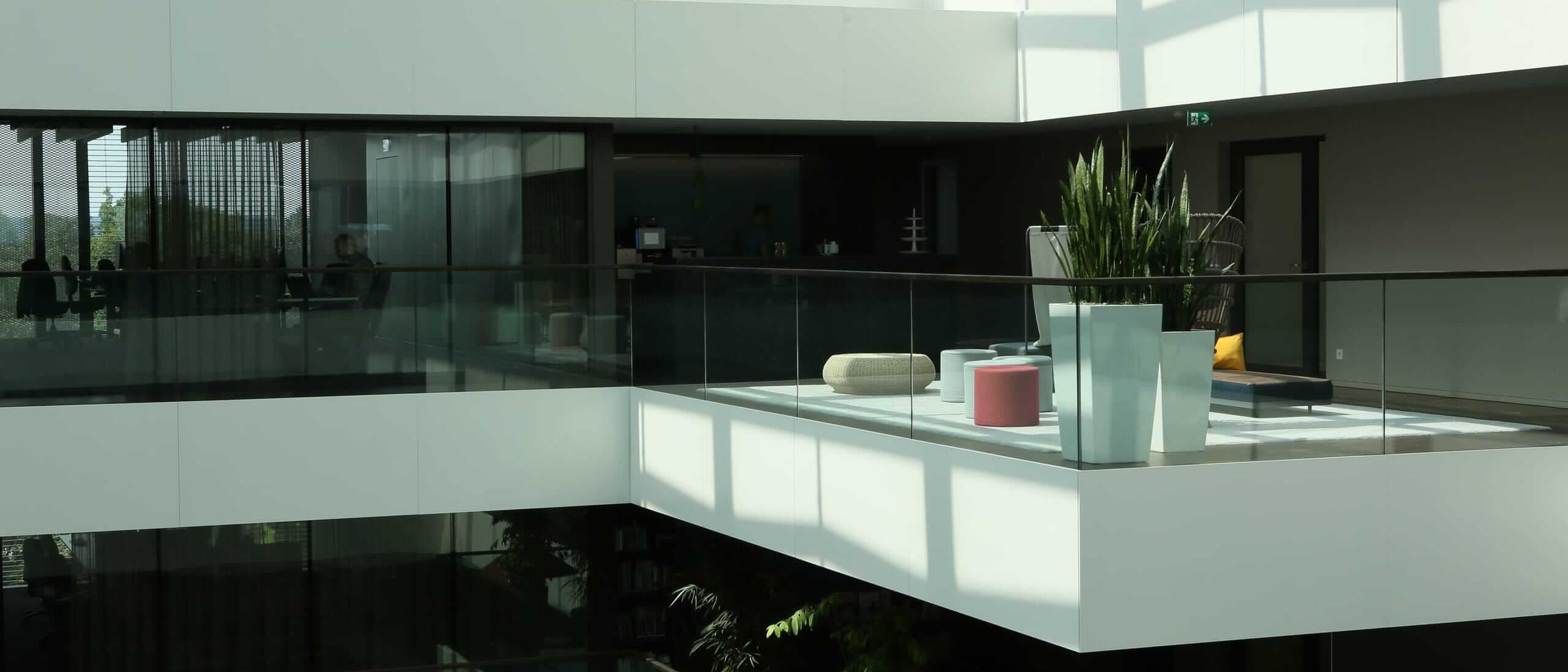 Galerie mit Loungebereich, Pflanzen und Glasbrüstung im Lichthof – AEB-Zentrale, Stuttgart