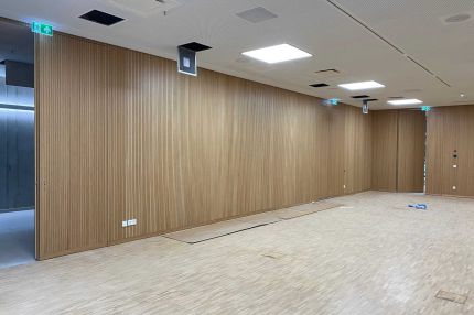Weiter Blick in den Saal mit Eichen-Schlitzplatten an den Wänden und Lochdecke – Technisches Rathaus Mannheim
