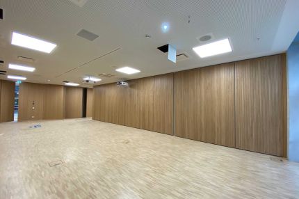 Großer Saal mit Wandelementen aus Eichen-Schlitzplatten und Lochdecke mit Beamer – Technisches Rathaus Mannheim