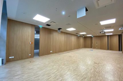 Saal mit Eichen-Schlitzplatten an den Wänden, Durchgang zum Flur und Lochdecke – Technisches Rathaus Mannheim