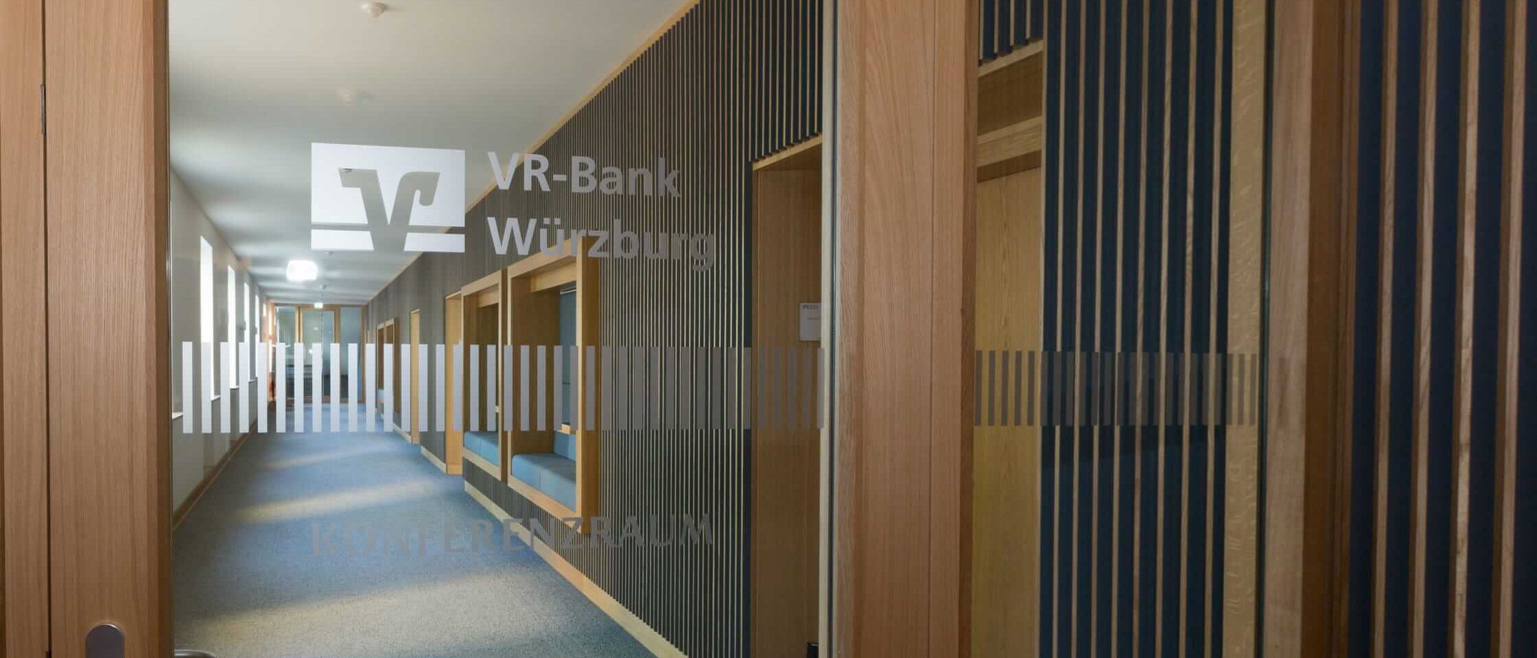 Blick durch Glastür mit VR-Bank-Logo in den Flur mit Lamellenwand – MOZ-Areal VR-Bank, Würzburg