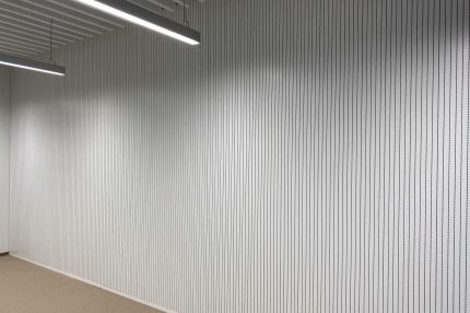 Raum mit weißer Schlitzplatten-Wandverkleidung, Pendelleuchten und Lamellendecke – Technisches Rathaus Mannheim