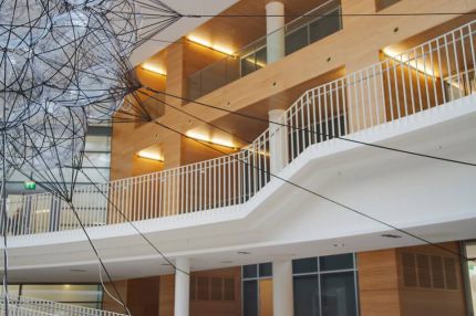 Halle mit hängender Skulptur, weißer Treppe und holzverkleideten Galerien – Europäisches Patentamt
