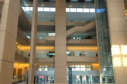 Lichthof mit holzverkleideten Pfeilern, Treppe und verglastem Eingangsbereich – Justizzentrum Bochum