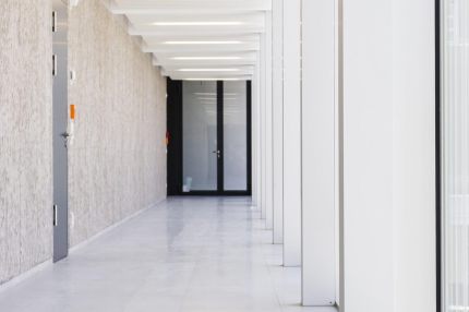 Flur an der Glasfassade mit weißer Lamellendecke und strukturierter Betonwand – Gymnasium Oberursel