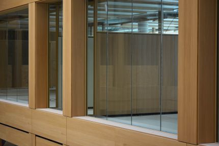 Detail der Verglasung mit Furnierrahmen und feingenuteter Wandverkleidung dahinter – IHK Nürnberg