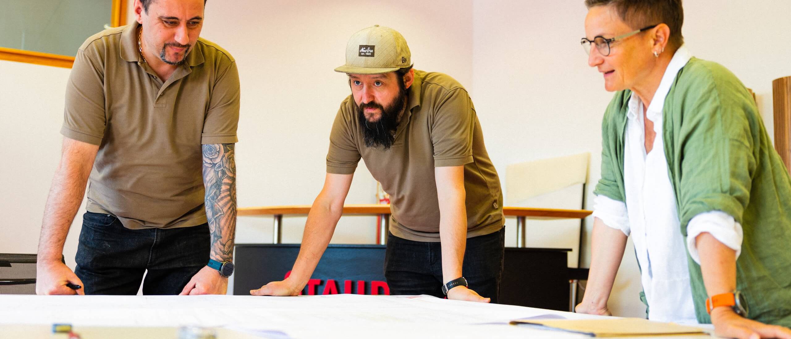 Drei Personen diskutieren Pläne zur Raumakustik bei Staudigel. | © Staudigel