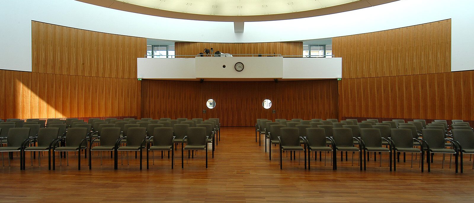 Saal mit Stuhlreihen, Holz-Wandverkleidung, Empore und ovaler Lichtdecke – IHK Potsdam