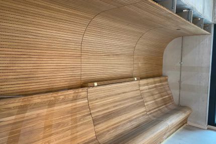 Seitlicher Blick auf die Sitznische mit geschwungener Eichen-Schlitzplatten-Verkleidung – Technisches Rathaus Mannheim