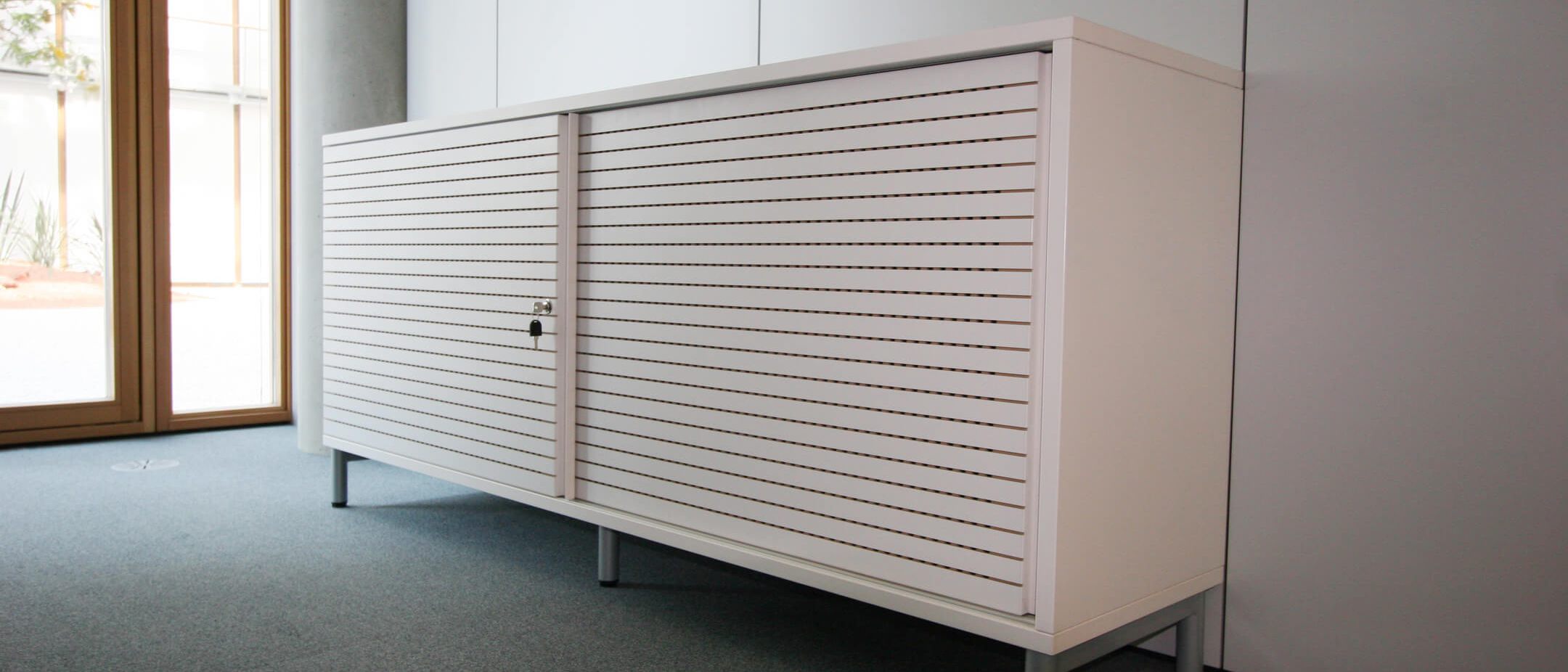 Ein modernes Sideboard von Staudigel mit geriffelter Oberfläche steht im hellen Raum.