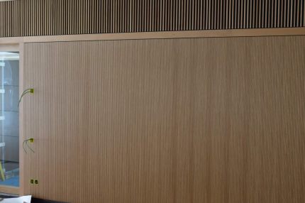 Wand mit Schlitzplatten in Holzfurnier und darüberliegendem Holzlamellenband – IHK Nürnberg