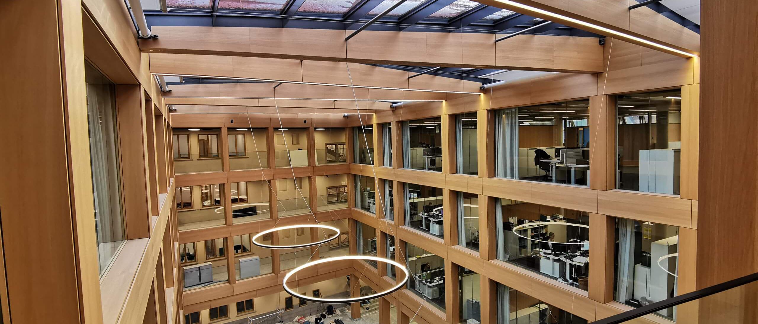 Fertiges Atrium mit Glasdach, holzfurniertem Fassadenraster und Ringleuchten – IHK Nürnberg