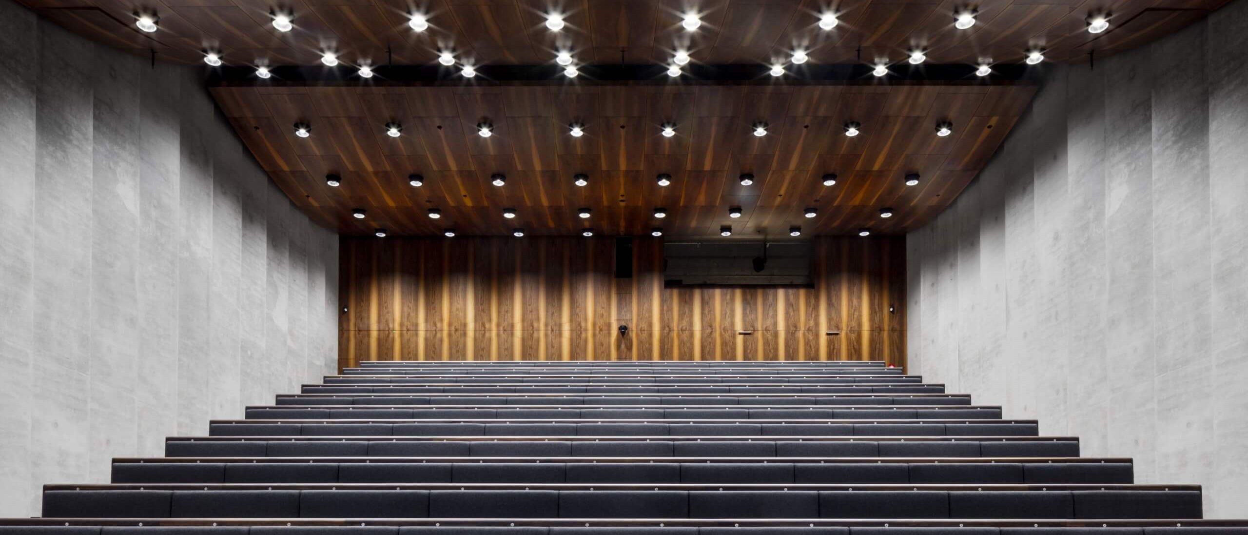 Auditorium mit Holzdecke, Downlights und Rückwand aus Nussbaum-Furnier – James-Simon-Galerie, Berlin