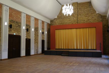 Festsaal mit Bühne, rotem Rahmen und goldenem Vorhang – Neues Schloss Bad Muskau
