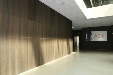 Foyer mit Wandverkleidung in dunklem Holzfurnier, Streiflicht und Firmenlogo – AEB-Zentrale, Stuttgart