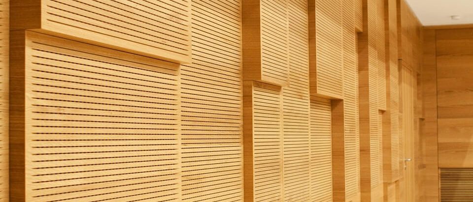 Schrägansicht der versetzt angeordneten Schlitzplatten aus Holz an der Saalwand – Musikschule Essenbach