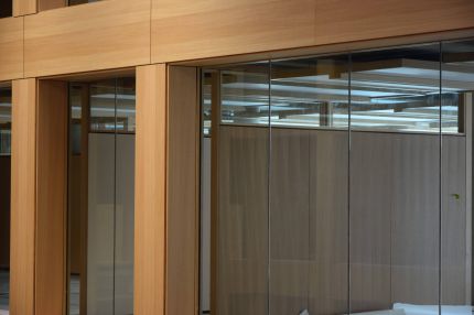 Detail furnierter Pfeiler und Glaswand, dahinter genutete Holzwandverkleidung – IHK Nürnberg
