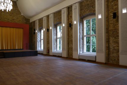 Festsaal mit Bühne, Rundbogenfenstern und Sichtmauerwerk – Neues Schloss Bad Muskau