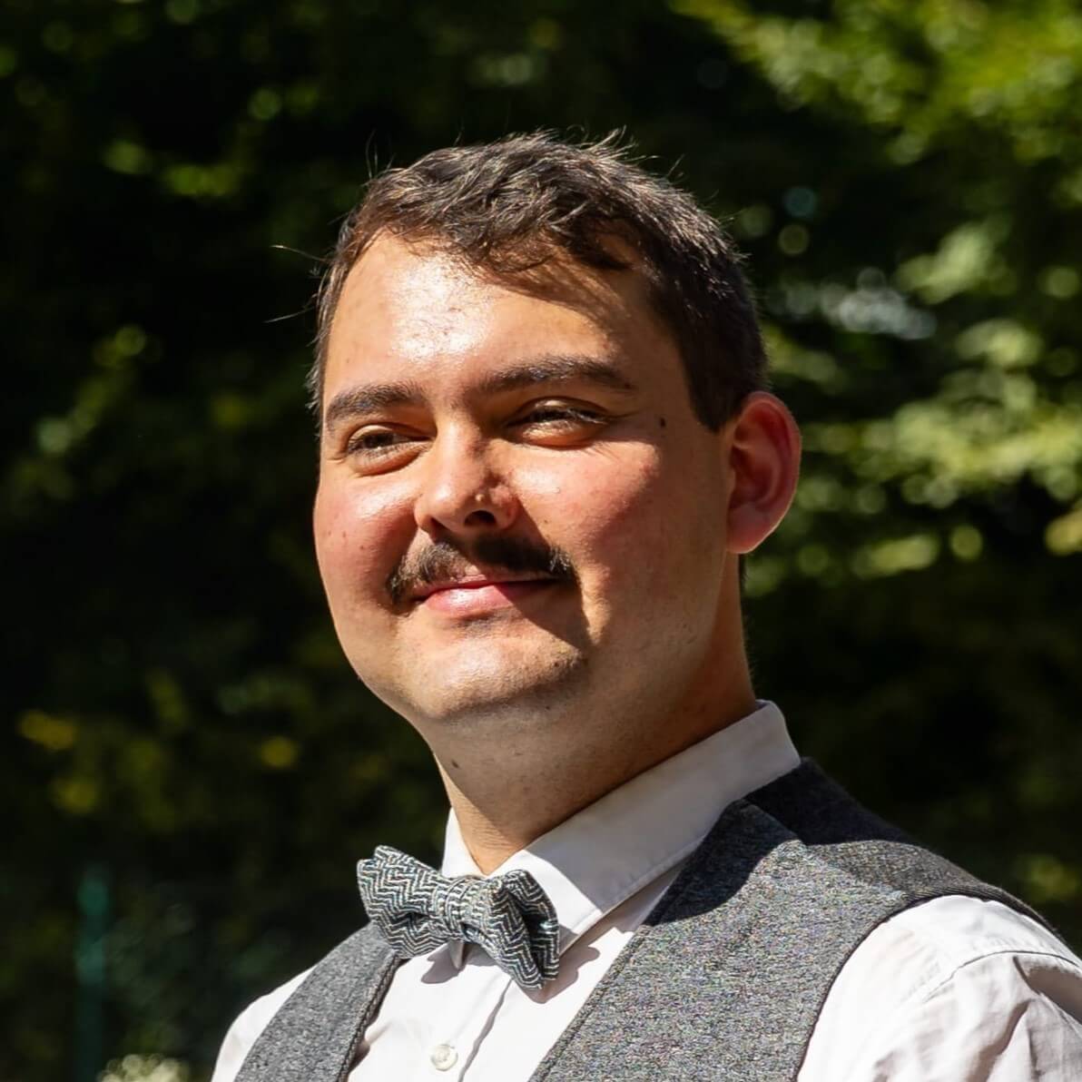 Marius Lösch lächelt im Freien, inspiriert von Staudigel und Raumakustik.